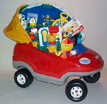 A Rainbow Hector is nestled into toddler's ride-in toy car, that is stuffed with baby items.
